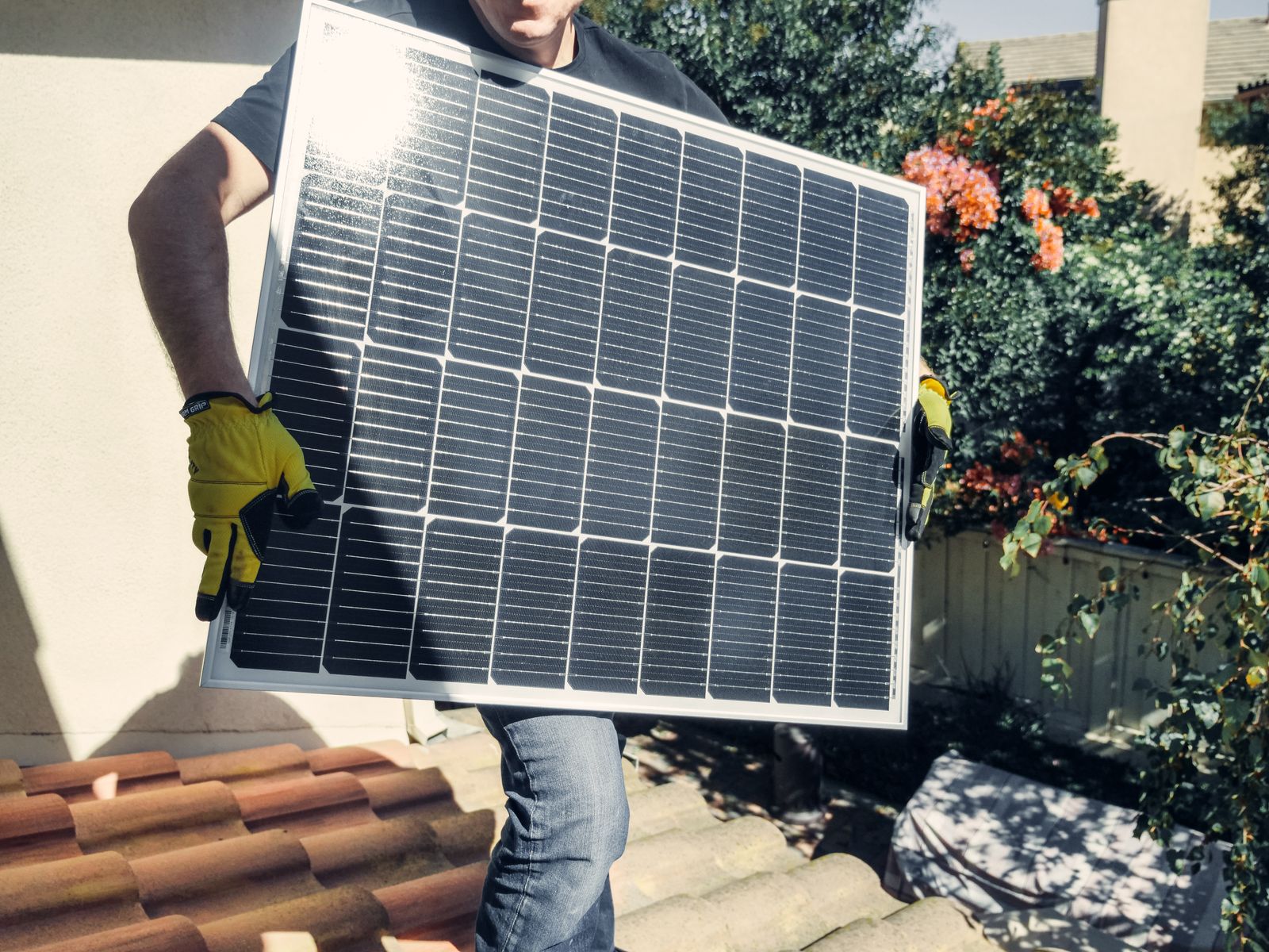 Técnico transportando un panel solar en una instalación residencial