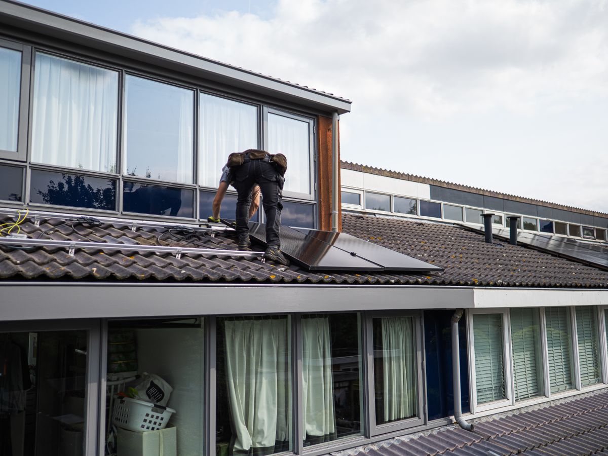 Técnico instalando un panel solar en un tejado residencial